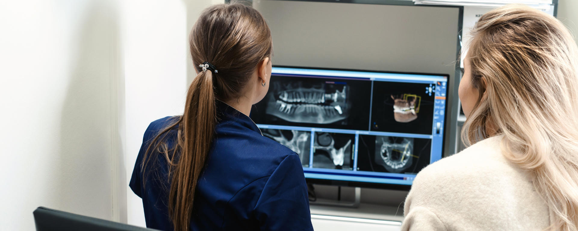 Two women are looking at x-rays of the teeth