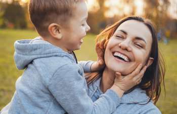 laughing young mom with baby in the park