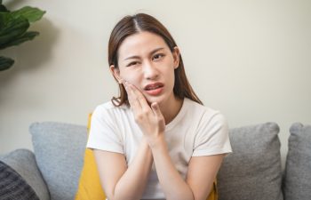Face expression suffering from sensitive teeth, Asian young woman touching cheek